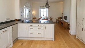 A spacious kitchen with a central island, white cabinetry, and a wooden floor. - The Lookout (Alnwick)