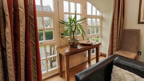 A cozy room with a wooden table, a potted plant, and a leather chair. - Lapwing Cottage (Bamburgh)
