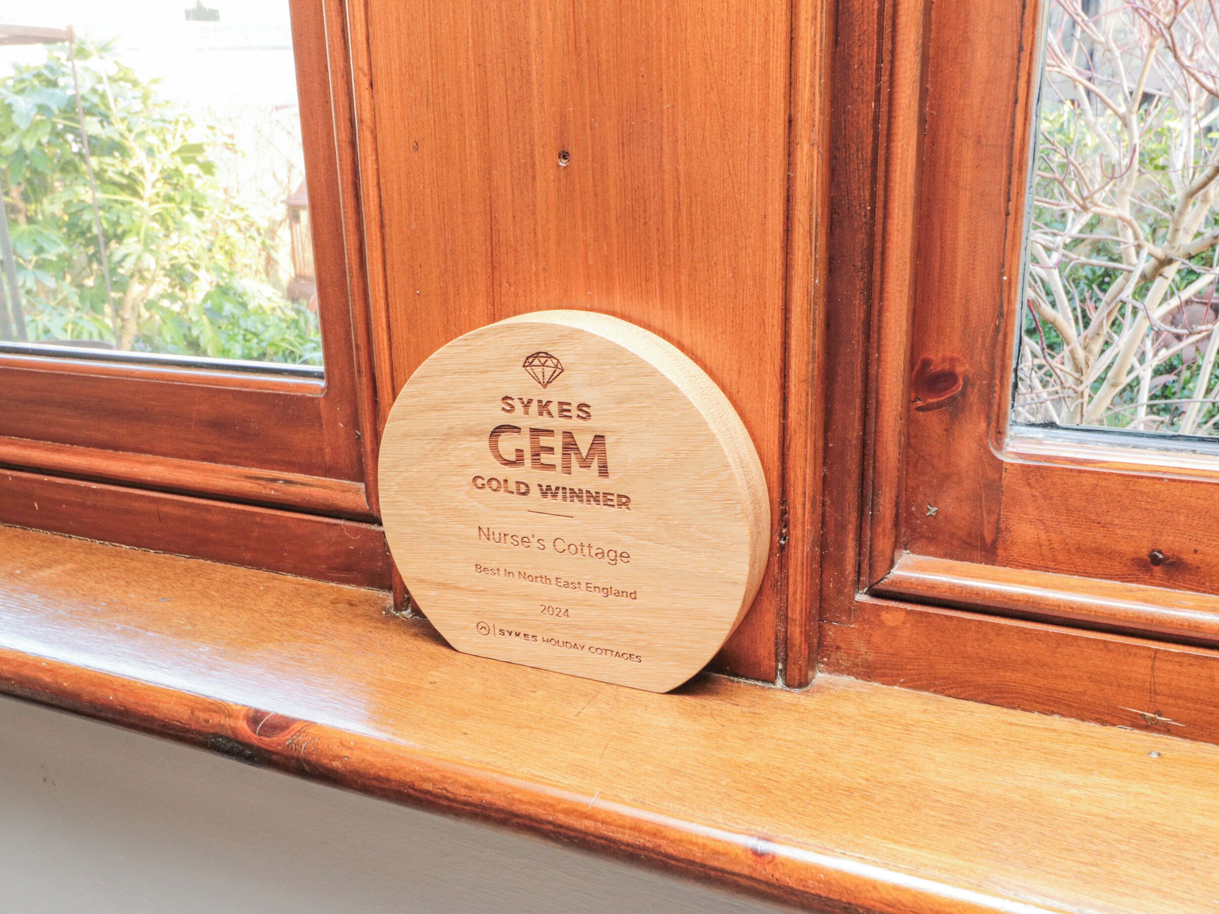 Une plaque en bois, fixée sur un rebord de fenêtre, porte une inscription indiquant que la « Résidence des infirmières » a reçu un prix d’or en 2024.