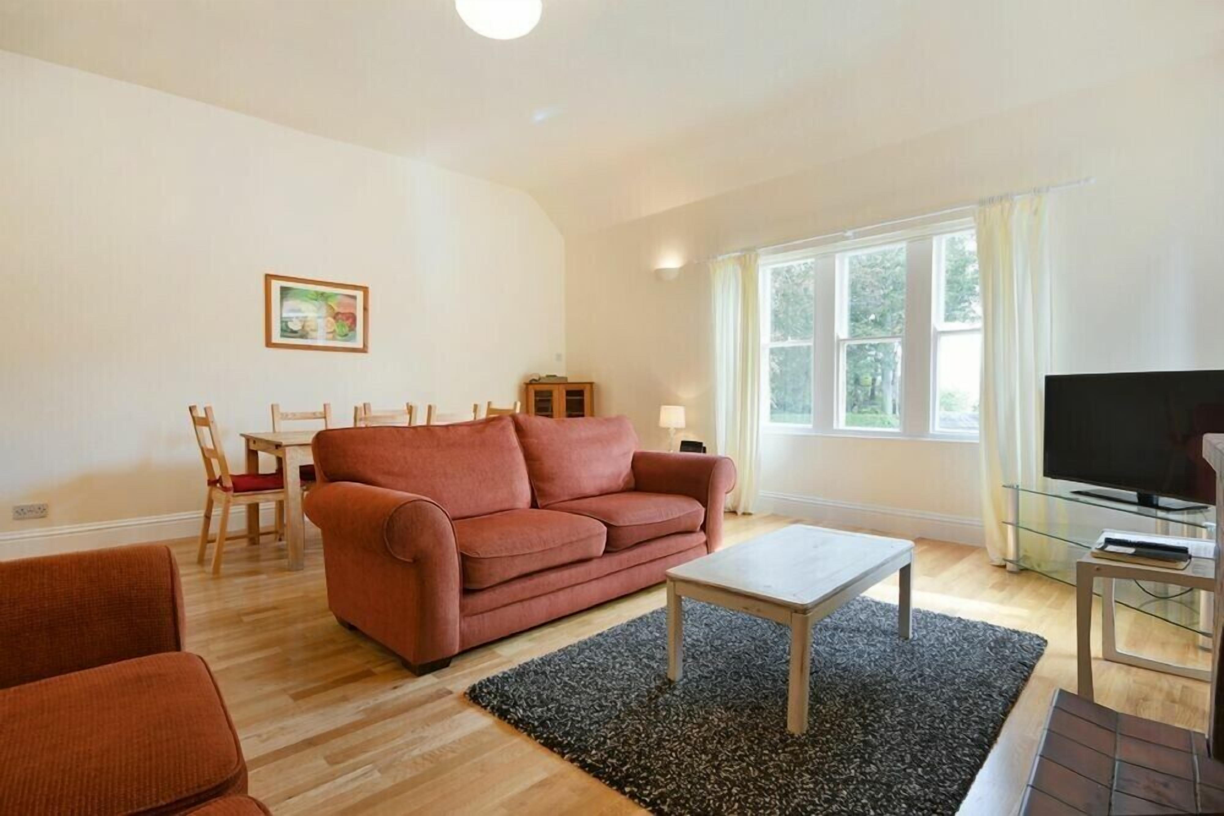 Ein Wohnzimmer mit einer Couch, einem Couchtisch, einem Fernseher und einem Essbereich mit Stühlen und Tisch.