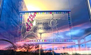 Placa para a Leazer Cottage, com borda decorativa e design floral.