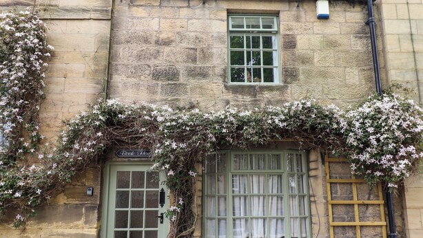 A stone building with a green door, a window with white curtains, and a sign reading "Book House". - The Book House (Morpeth)