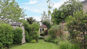 A well-maintained garden with a stone wall, a wooden fence, and a variety of plants and shrubs. - The Book House (Morpeth)