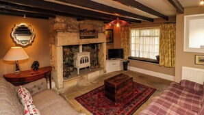 A cozy living room with a stone fireplace, a television, and comfortable seating. - The Book House (Morpeth)