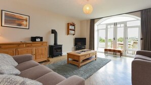 Ein Wohnzimmer mit einer Couch, Couchtisch, Fernseher, Bücherregal und Kamin.