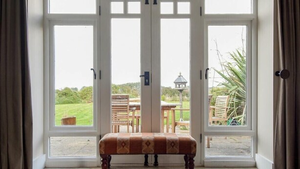 Ein Zimmer mit einem großen Rundbogenfenster, einer Sitzbank und Blick auf einen Garten.
