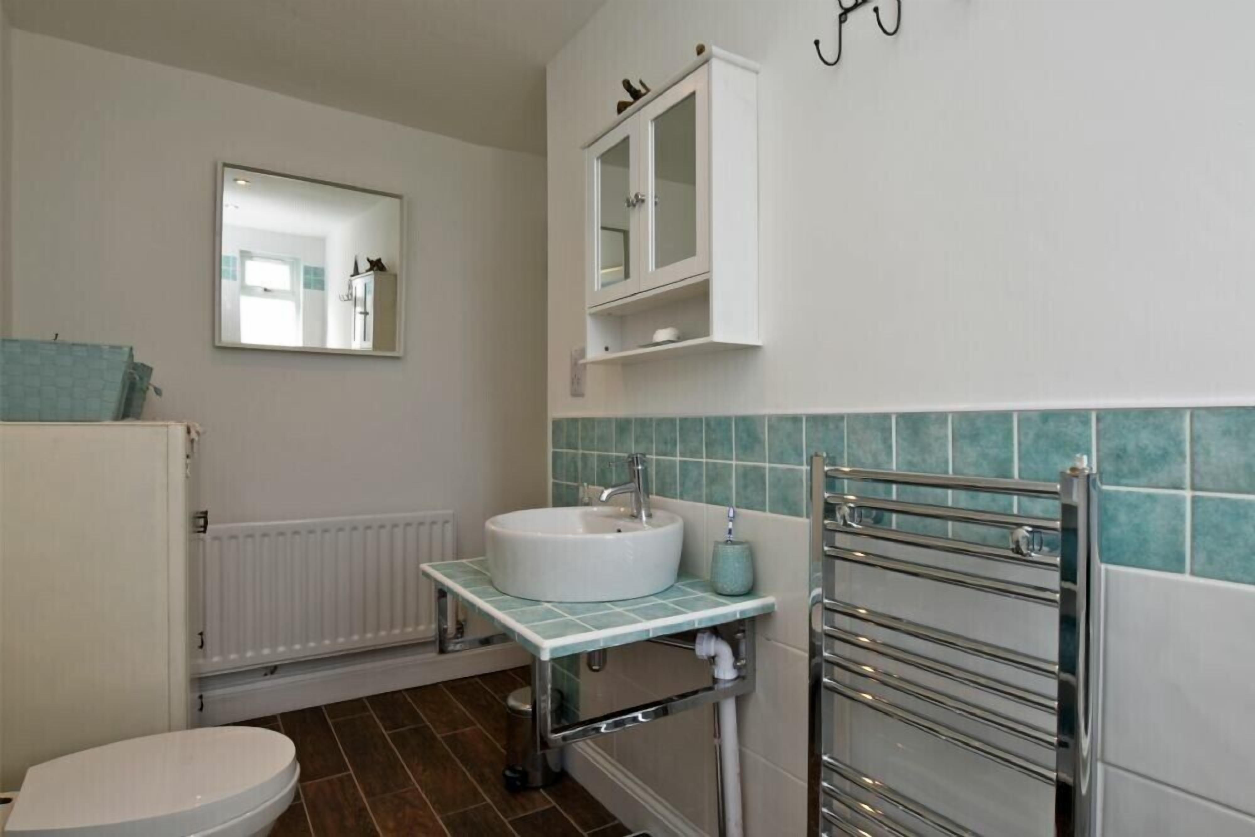 Une salle de bain avec un lavabo blanc, un miroir, un meuble et un porte-serviettes.