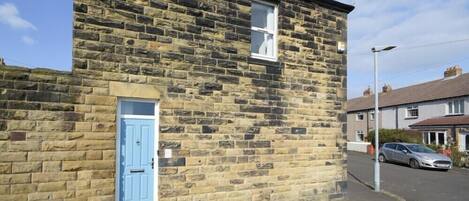 A stone building with a blue door and a small window.