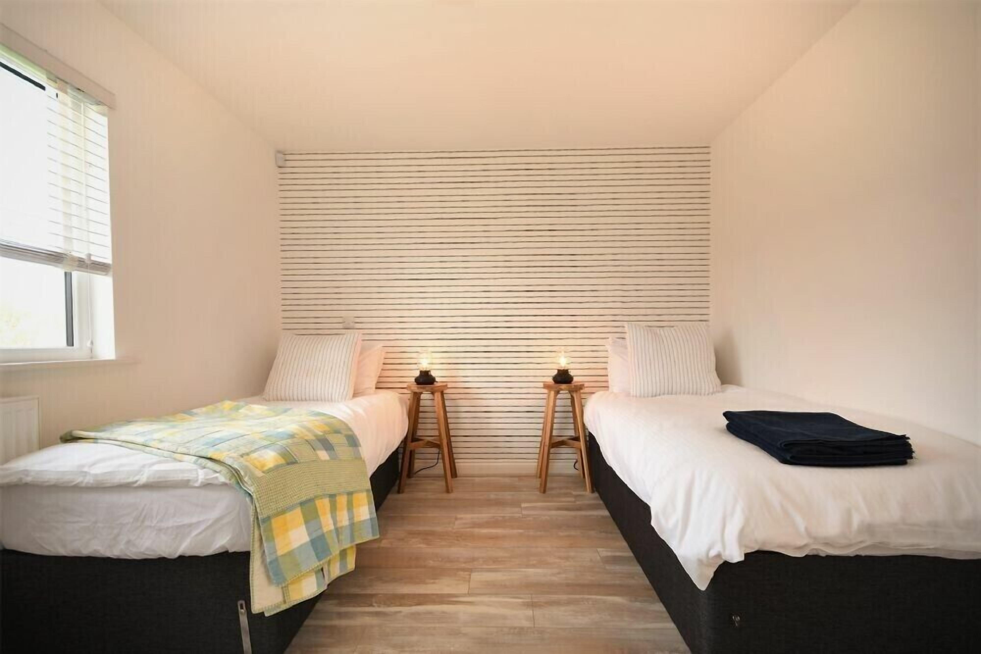 A bedroom with two single beds, a window, and a slatted headboard.