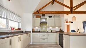 Une cuisine moderne avec des armoires blanches, un plan de travail en bois et une cuisinière intégrée.