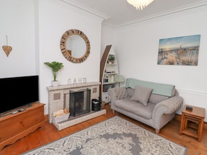 A living room with a fireplace, a sofa, a television, and a painting on the wall.