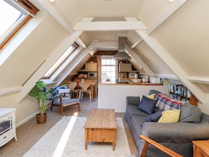 Un accogliente loft con angolo pranzo, angolo cottura e soggiorno con divano e tavolino.