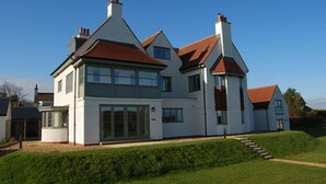 A large, modern house with multiple windows and a prominent chimney. - Sandpiper (Bamburgh)