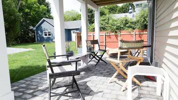 An outdoor patio with a covered seating area, a small table, and a chair.