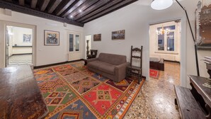 Una stanza con un divano marrone, un tappeto decorato, mobili in legno e opere d'arte alle pareti.