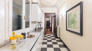 Una cucina con pavimento a scacchi, un piano di lavoro in marmo e un quadro appeso al muro.
