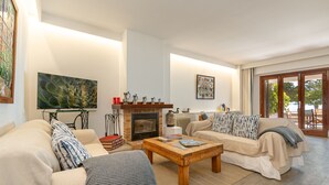 Un salon avec une cheminée, des canapés, une table basse et un téléviseur.