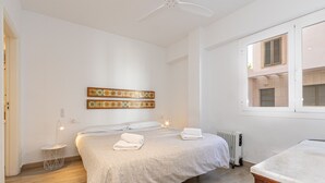 Une chambre à coucher comprenant un lit, deux panneaux décoratifs fixés au mur, une table de chevet, un radiateur et une fenêtre avec des volets.