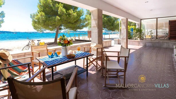 Un espace extérieur aménagé avec des sièges et offrant une vue sur la mer, comprenant une table avec des chaises, un vélo et une plante en pot.