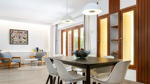 Un espace repas moderne avec une table en bois, des chaises blanches et des luminaires suspendus.
