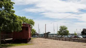 A gravel road with a red train car on the left and a wooden fence in the middle.
