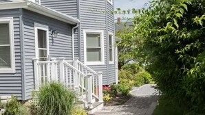 A two-story house with a front porch and a pathway leading to the entrance. - Blue Bay Dream w/ Seasonal Outdoor Jacuzzi, Cabana + Office (Greenport,)