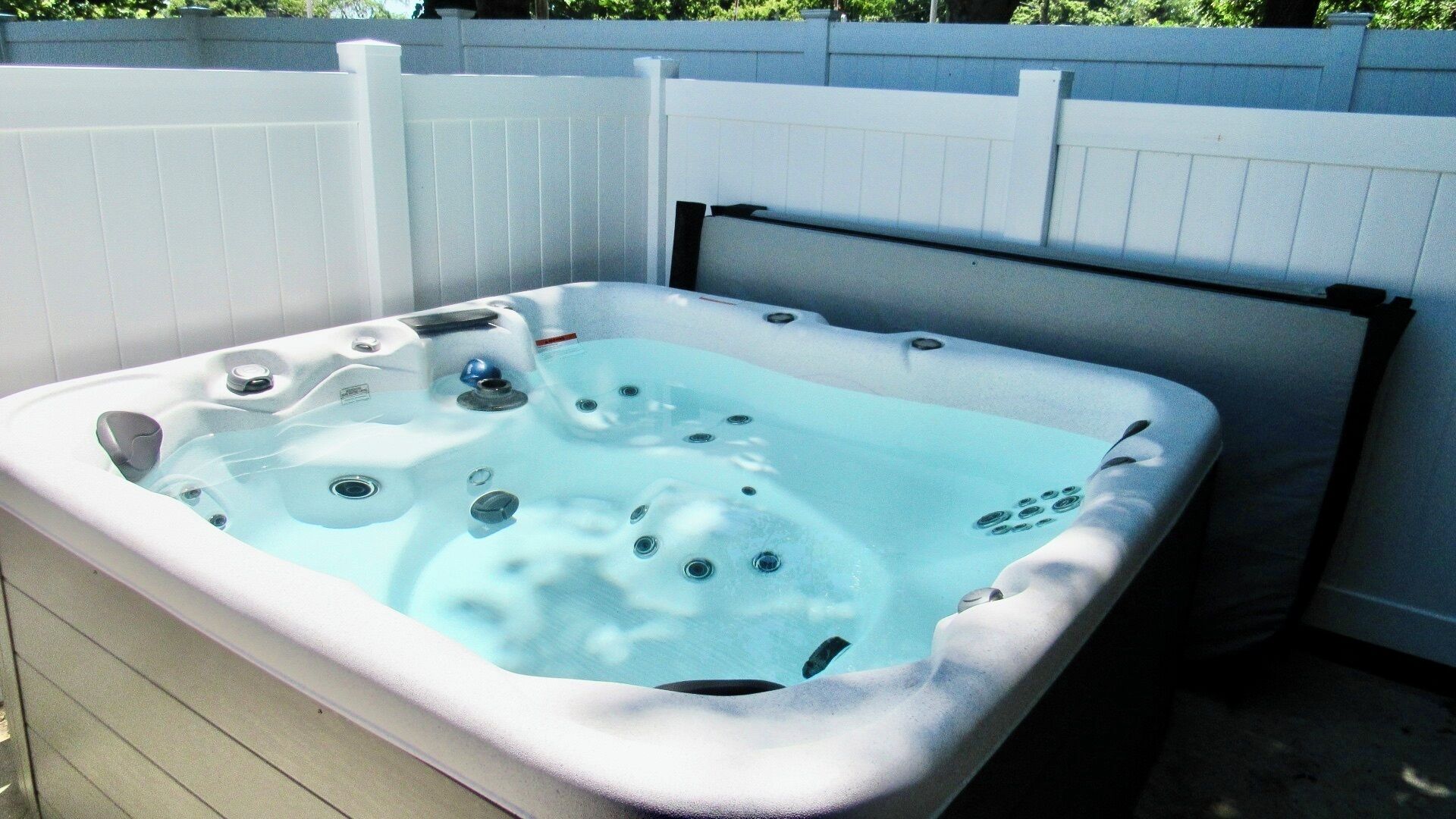 A hot tub with a white exterior, built-in jets, and a black headrest.