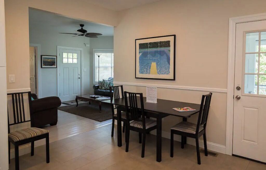 A dining area with a table and chairs, a ceiling fan, and a framed artwork on the wall.