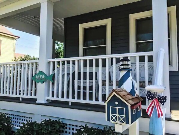 A porch with a white railing, a small blue house decoration, and a 'Gone' sign.