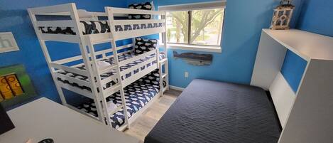 Une chambre avec des lits superposés, un bureau, une chaise, une fenêtre et une petite étagère sur laquelle se trouve une lanterne.