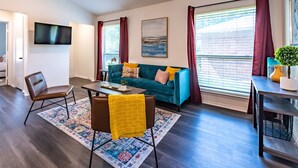 A modern living room with a sofa, coffee table, and a TV mounted on the wall. - Cozy 2Bed/2Bath - Modern & Spacious - Central Frisco (frisco)