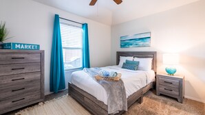 A bedroom with a bed, a nightstand, a dresser, a ceiling fan, and a window with curtains. - Cozy 2Bed/2Bath - Modern & Spacious - Central Frisco (frisco)