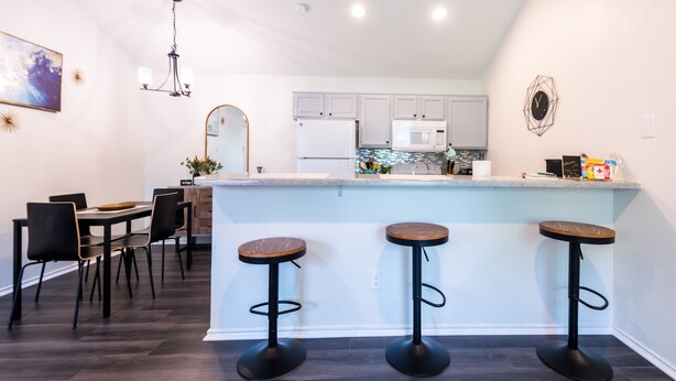 A modern kitchen with a central island, bar stools, and a dining area with chairs. - Cozy 2Bed/2Bath - Modern & Spacious - Central Frisco (frisco)
