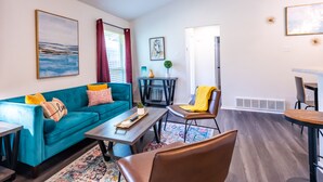 A modern living room with a teal sofa, a coffee table, and a dining area with a table and chairs. - Cozy 2Bed/2Bath - Modern & Spacious - Central Frisco (frisco)