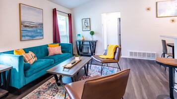 Un salon moderne avec un canapé de couleur turquoise, une table basse et un coin repas comprenant une table et des chaises.