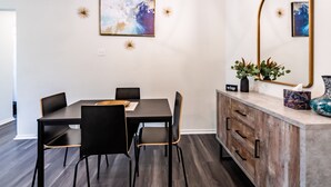 A dining area with a dark wooden table and chairs, a modern chandelier, and wall-mounted artwork. - Cozy 2Bed/2Bath - Modern & Spacious - Central Frisco (frisco)