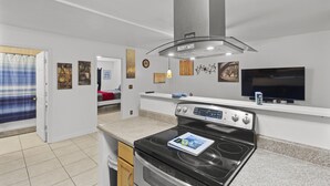 A modern kitchen with a stove, oven, and a TV mounted above the counter.