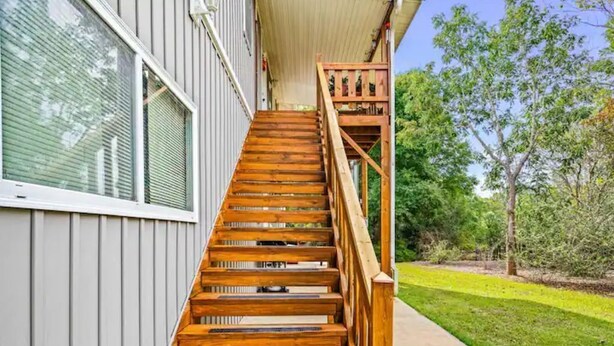 A wooden staircase leading to a house with a covered porch.