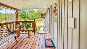 A wooden deck with a bench and table, potted plants, and a view of the surrounding landscape.