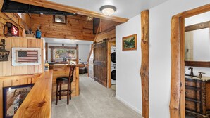 A rustic interior with wooden beams, a bar area, a washing machine, and a large mirror. - "The Lodge"-  APT w/Loft Bedroom, Walnut Bar, Quiet Setting, Covered Parking (Enterprise)