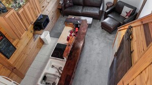 A compact kitchen with a central island, a dining area with a sofa, and a wooden ceiling. - "The Lodge"-  APT w/Loft Bedroom, Walnut Bar, Quiet Setting, Covered Parking (Enterprise)
