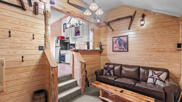 A cozy cabin interior with a wooden staircase, a brown leather sofa, and a wooden dining table. - Cozy Apt w/Master BR + 2 Bed Kids Loft. Covered Parking/Deck/BBQ area & Firepit (Enterprise)