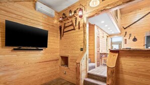 A wooden interior with a TV mounted on the wall, a staircase, and a wooden bench. - Cozy Apt w/Master BR + 2 Bed Kids Loft. Covered Parking/Deck/BBQ area & Firepit (Enterprise)