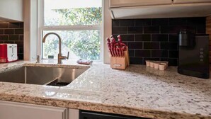 A kitchen with a granite countertop, stainless steel sink, and a coffee maker. - Cozy Apt w/Master BR + 2 Bed Kids Loft. Covered Parking/Deck/BBQ area & Firepit (Enterprise)