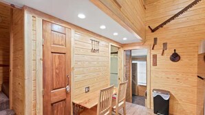 A wooden interior with a dining area, a door, and a trash bin. - Cozy Apt w/Master BR + 2 Bed Kids Loft. Covered Parking/Deck/BBQ area & Firepit (Enterprise)