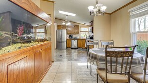 A kitchen with wooden cabinets, a refrigerator, a dining table with chairs, and a chandelier. - Sevierville Home: Lookout Deck, 10 Mi to Dollywood (Sevierville)