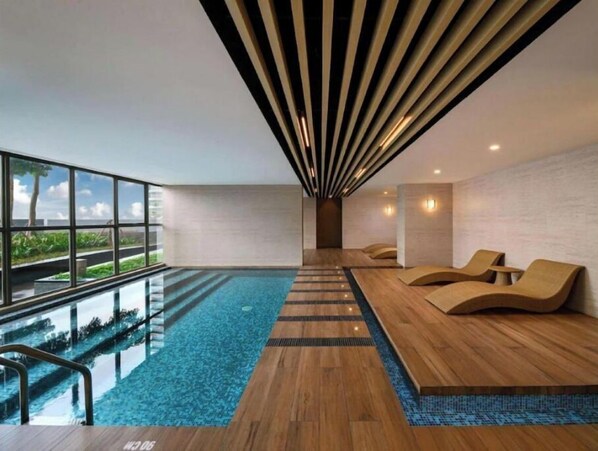 Relax by the pool with a stunning sea view, surrounded by lounge chairs and a mosaic tile design.