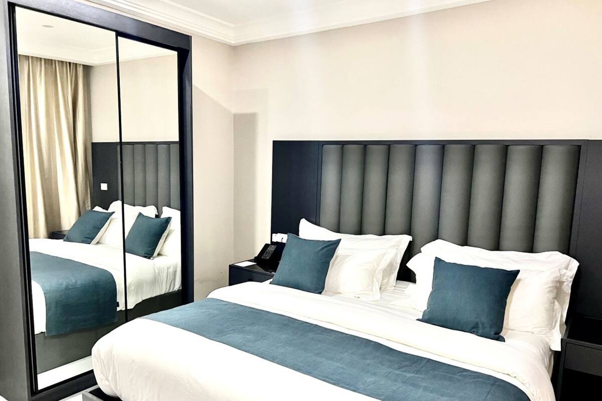Een moderne hotelkamer met een groot bed, een nachtkastje, een spiegel en uitzicht op het interieur van de kamer.