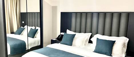 A modern hotel room with a large bed, a nightstand, a mirror, and a view of the room's interior.