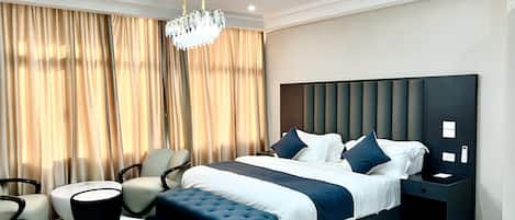A modern bedroom with a large bed, a chandelier, and a view of the city.
